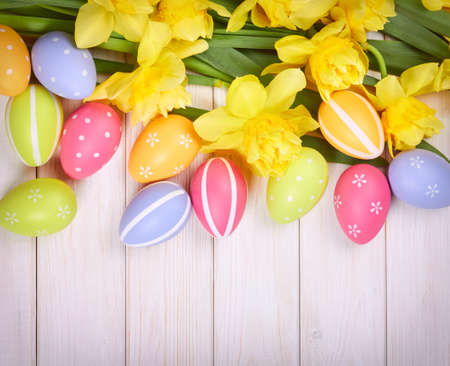 Easter eggs on wooden table with Yellow narcissus