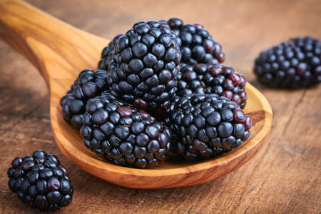 Blackberries in a wooden spoon on dark backgroundの写真素材