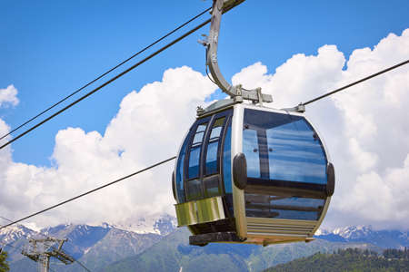 Cabin of ropeway in mountains among clouds in the sky