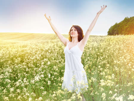 Woman in field with yellow flowers at summer sunset.の写真素材