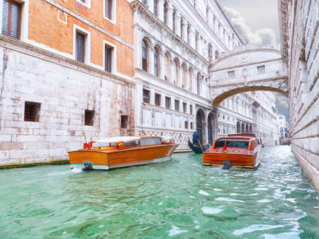 Traditional boats taxi passing over Bridge of Sighs in Veniceの写真素材