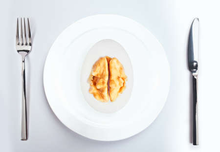 Concept of a clever protein diet. Boiled Egg in a cut with walnut inside in a plate on the table.の写真素材