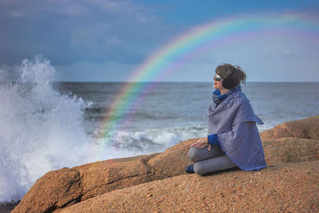 Woman On rocky Beach, rainbow over the stormy seaの写真素材