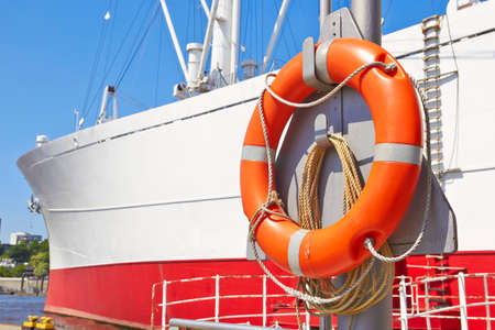 Orange lifebuoy hanging on big ship hullの写真素材
