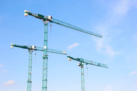 Three industrial construction tower cranes against blue skyの写真素材