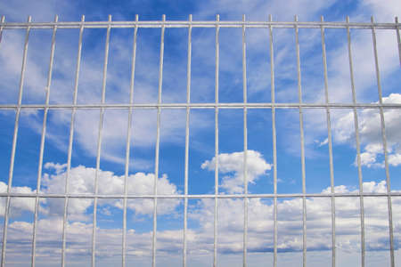 blue sky behind a wire lattice, looking through a wire up to the blue skyの写真素材