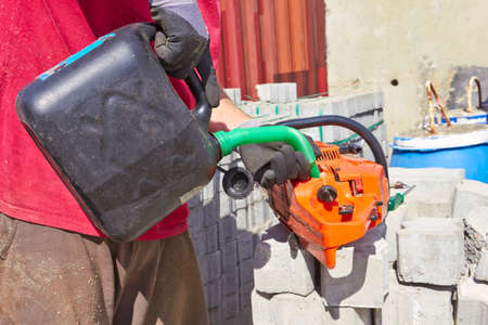 Worker filling fuel Into the chainsawの写真素材
