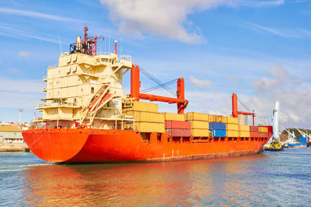 Tugboat pulls a large cargo ship to port. Transportation and logistics workの写真素材