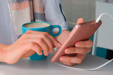 Female hands using smartphone. Cup of coffeeの写真素材
