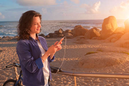 Beautiful woman in headphones listening to music and using smartphoneの写真素材