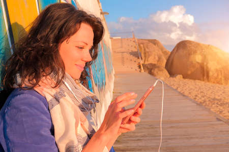 Smiling caucasian woman in headphones using smartphoneの写真素材