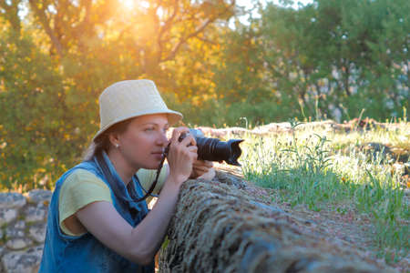 Female photographer taking photo in beautiful countrysideの写真素材