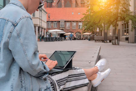 Young womanin in denim jacket sitting and typing on laptopの写真素材