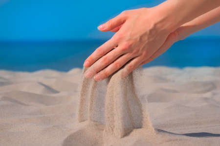 Sand in a handful of hands. Close up against seascape backgroundの写真素材
