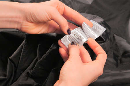 Female hands showing Clothing Label. Showing Washing Instructionの写真素材
