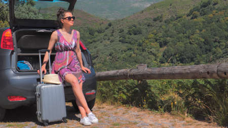 Woman traveler sitting on hatchback car outdoorの写真素材