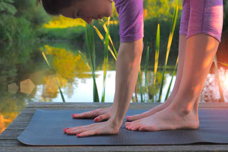 Woman doing stretching exercises on wooden pier at the lake.の写真素材