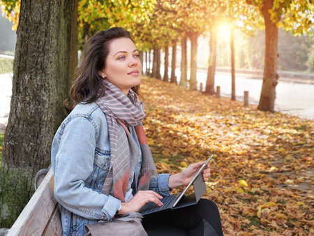 Cute woman with white laptop in the parkの写真素材