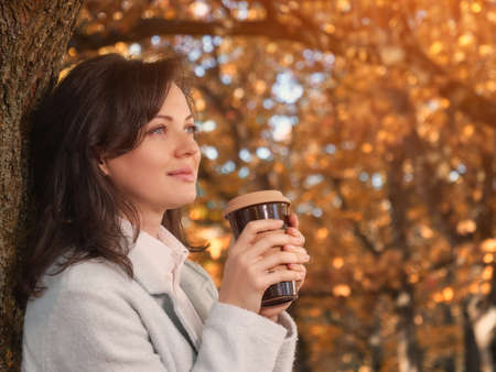 Beautiful woman drinking coffee outdoor enjoying her morning coffee.の写真素材
