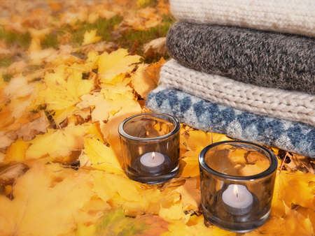 Yellow autumn leaves with candles, warm cozy sweaters autumn clothesの写真素材