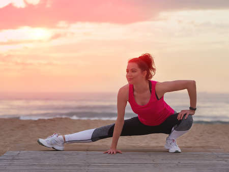Beautiful woman doing yoga fitness exercise in sport clothes on a wooden pier.の写真素材