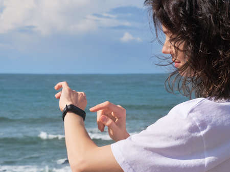 Woman looking at heart rate monitor watch outside jogging on beach.