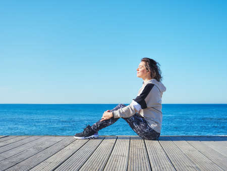 Woman on a wooden pier. Yoga, sport, vacation and freedom concept.の写真素材