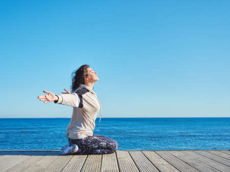 Woman on a wooden pier. Yoga, sport, traveling and freedom concept.