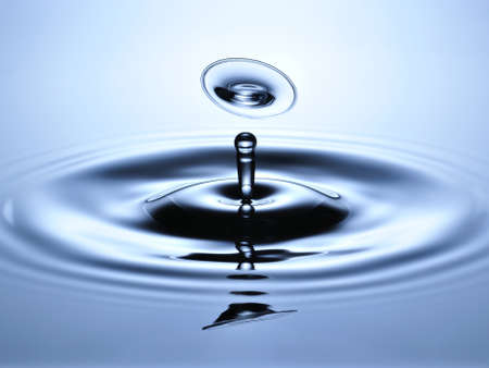 A small water drop fall on water surface and jump back to collide with the second one, forming a disk shaped splash の写真素材