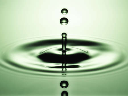A small water drop fall on water surface and jump back before the second one to collide with it の写真素材