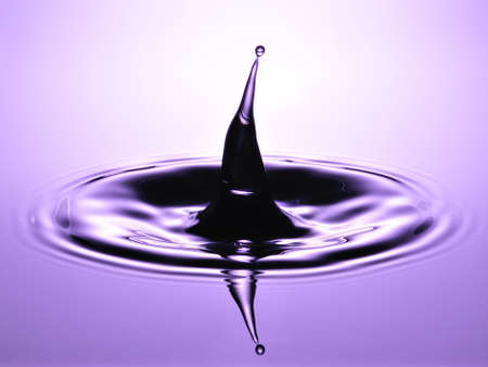 A small water drop fall on water surface and the splash jump to form a good clear, beautiful shape の写真素材
