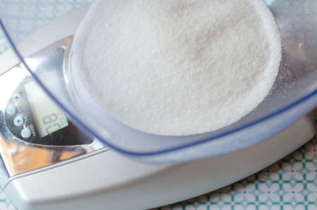 Weighing sugar to make a dessert with the kitchen scaleの写真素材