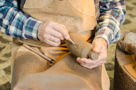 Old hands of a potter shaping a clay figure