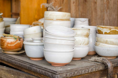 Set of white-painted ceramic bowls on a wooden table.の写真素材