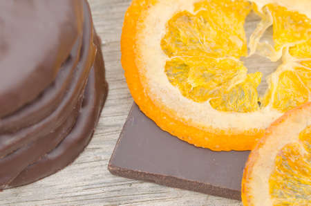 Candied orange slices covered with chocolate on wood table, close up view.の写真素材