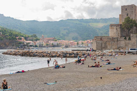 COLLIOURE, FRANCE - SEPTEMBER 18th, 2018: Tourists relax in the beach in the small village of...