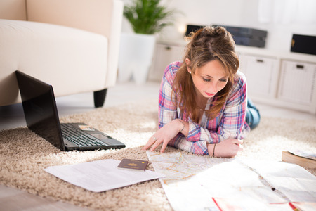 Cheerful young women at home, preparing at tripand buying on internetの写真素材