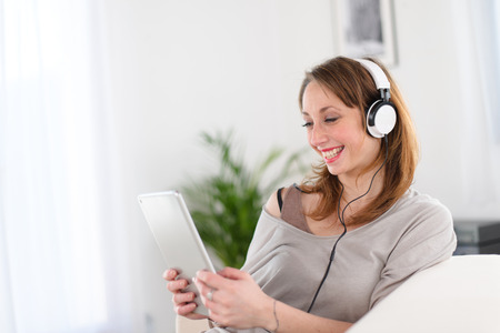 cheerful young women at home listenig to music on her computer tabletの写真素材