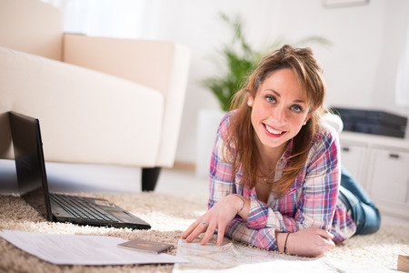 Cheerful young women at home, preparing at tripand buying on internetの写真素材