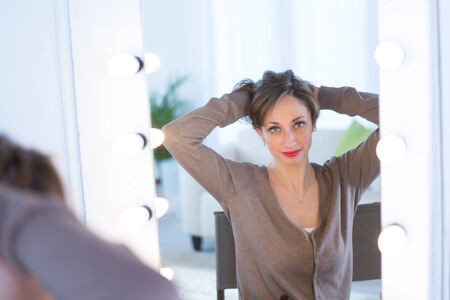 cheerful young women adjusting her make-up in a make-up mirror の写真素材