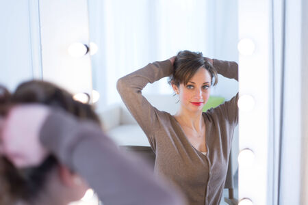 cheerful young women adjusting her make-up in a make-up mirror の写真素材