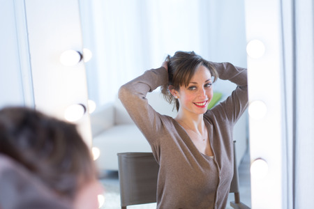 cheerful young women adjusting her make-up in a make-up mirror の写真素材