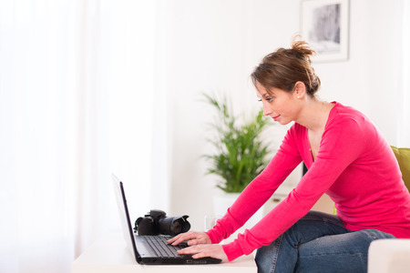 cheerful young women photographer working at home on her computerの写真素材