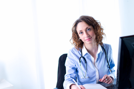 portrait of a beautiful female doctor writing down の写真素材