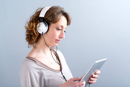isolated portrait of a beautiful young woman playing with tablet computerの写真素材