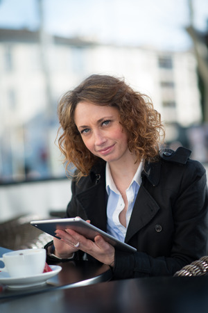 portrait of a beautiful young woman outside playing with tablet computerの写真素材