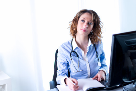 portrait of a beautiful female doctor writing down の写真素材