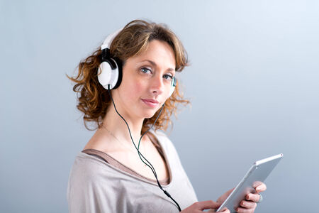 isolated portrait of a beautiful young woman playing with tablet computerの写真素材