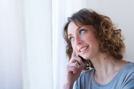 isolated portrait of a beautiful young woman  having telephone conversationの写真素材