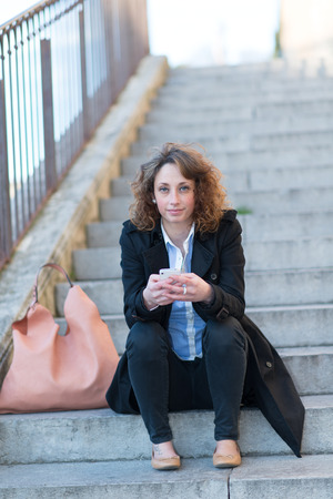 beautiful young woman siting in a staircase outisdeの写真素材
